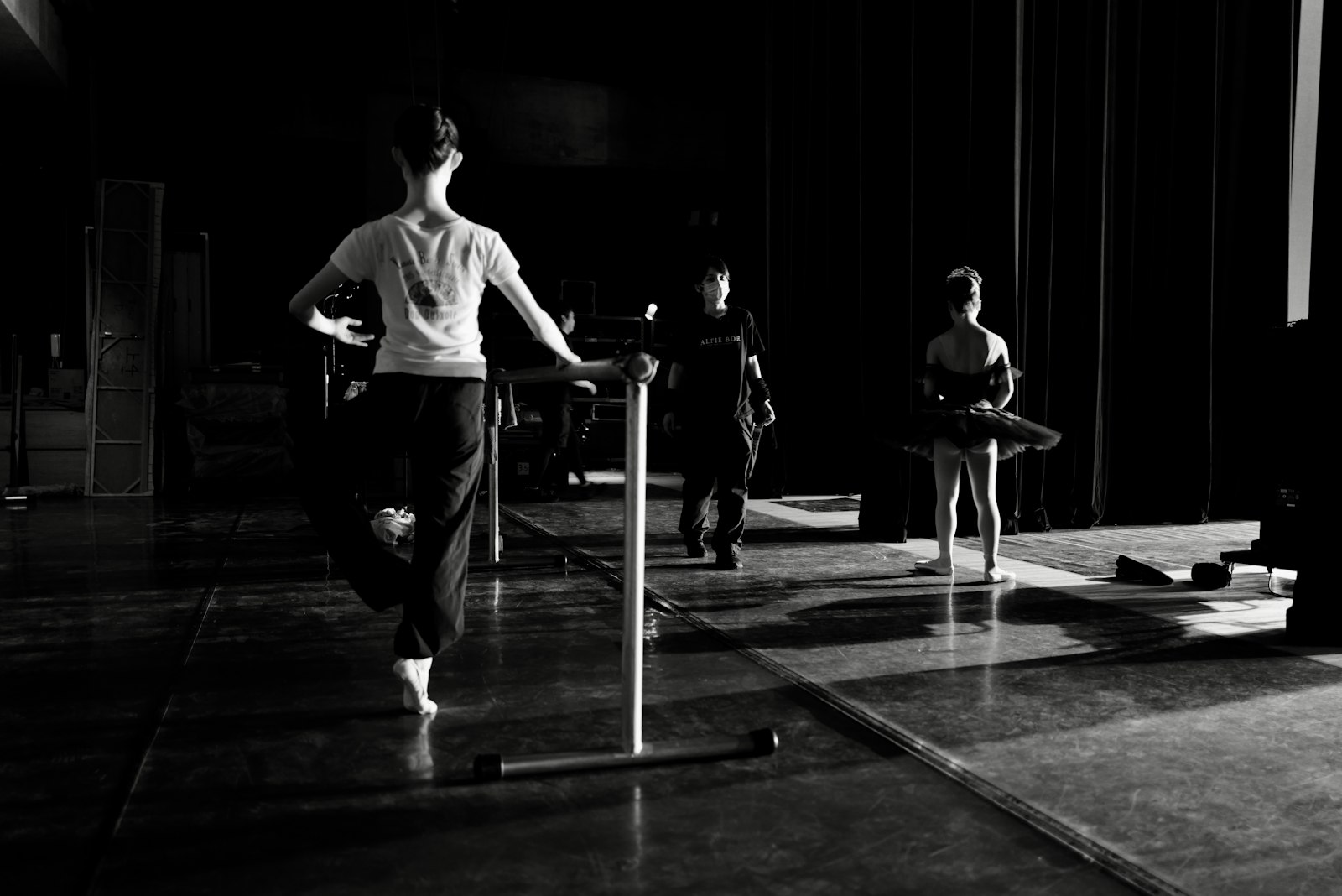 Dancers warming up backstage in a shaft of light