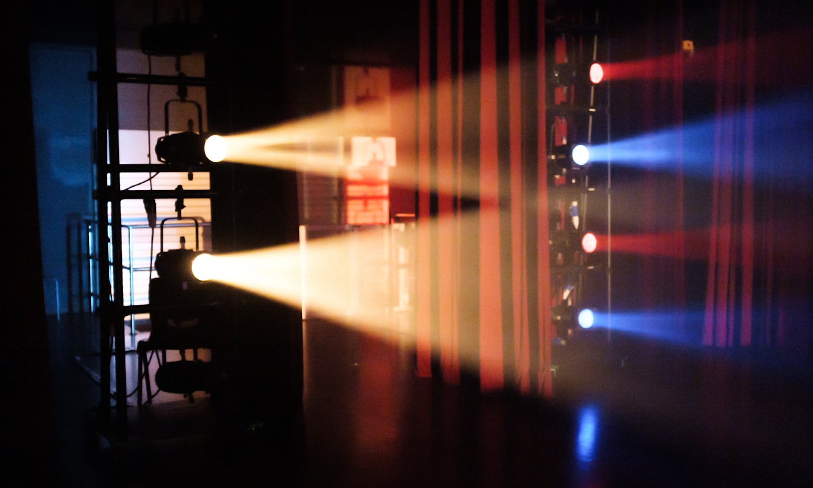 Warm theatre light beams cutting through haze backstage
